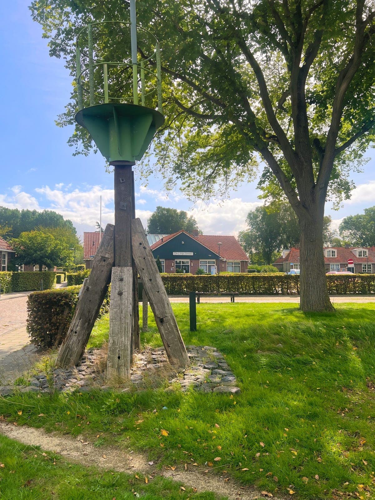 Een oud baken met een groene kop op het grasveld tegenover het hotel