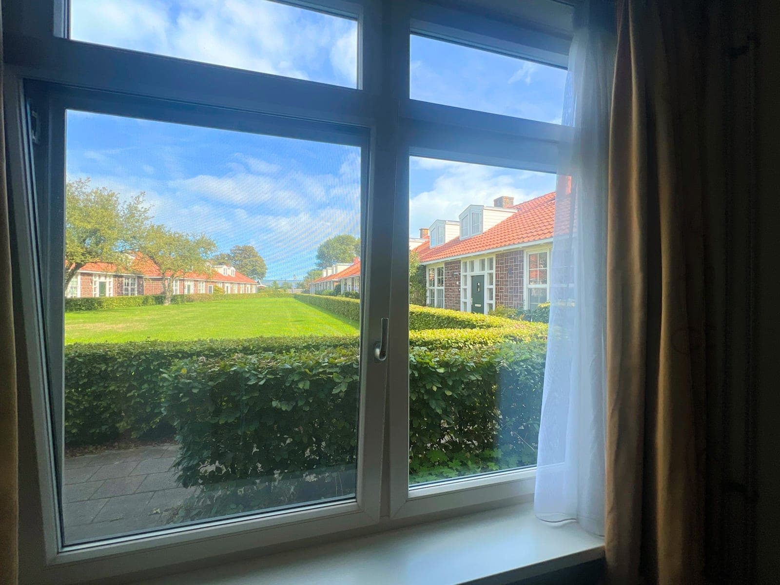 Uitzicht vanuit het raam op het grasveld en de rij woningen
